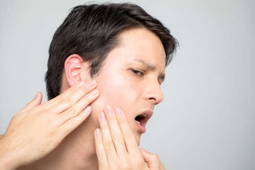 a woman is facing severe TMJ pain
