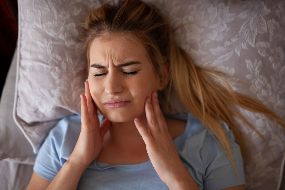 a woman is suffering from TMJ pain